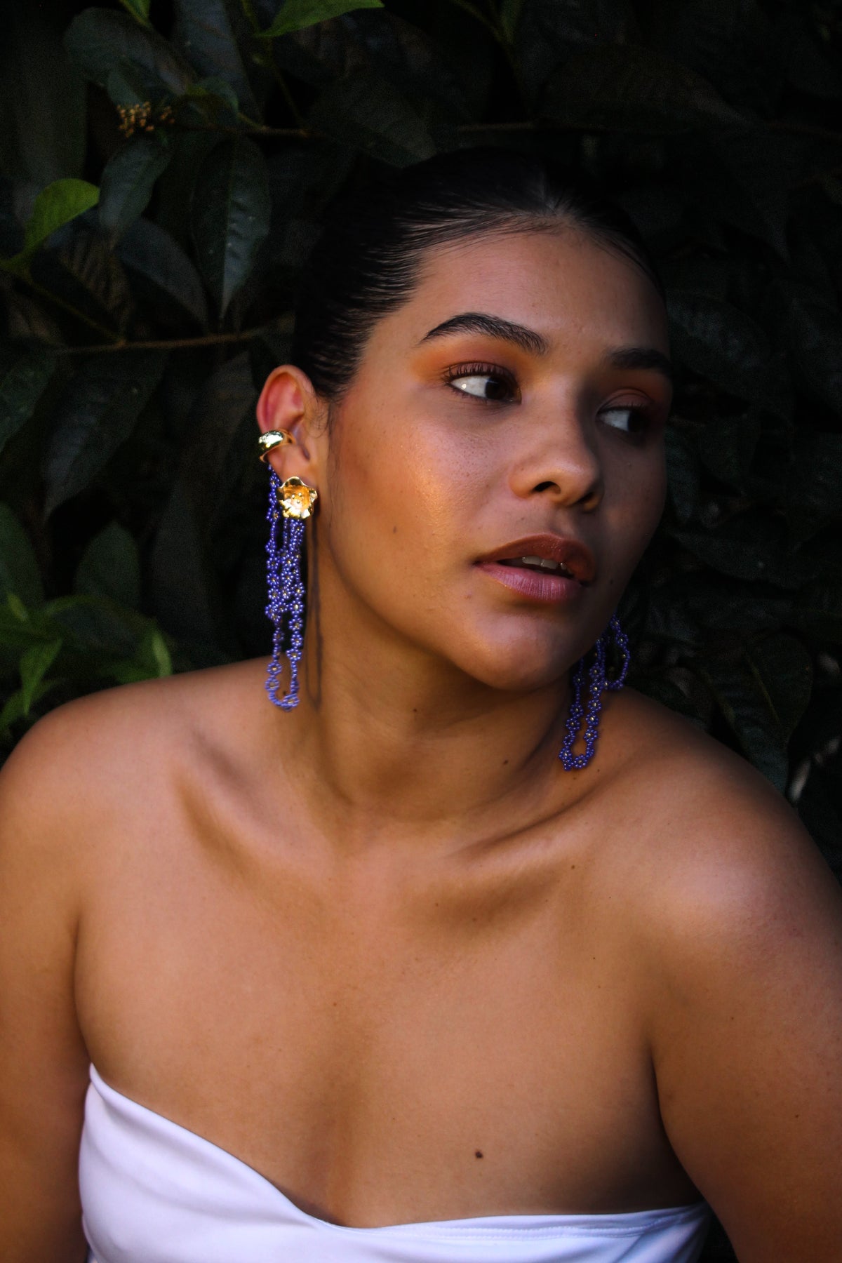 Woman wearing long blue earrings with a dark background