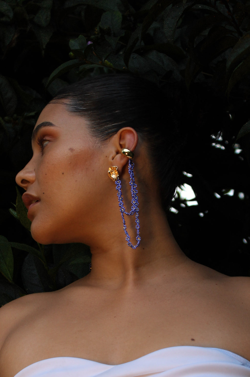 Woman wearing a gold and blue earring with a dark background