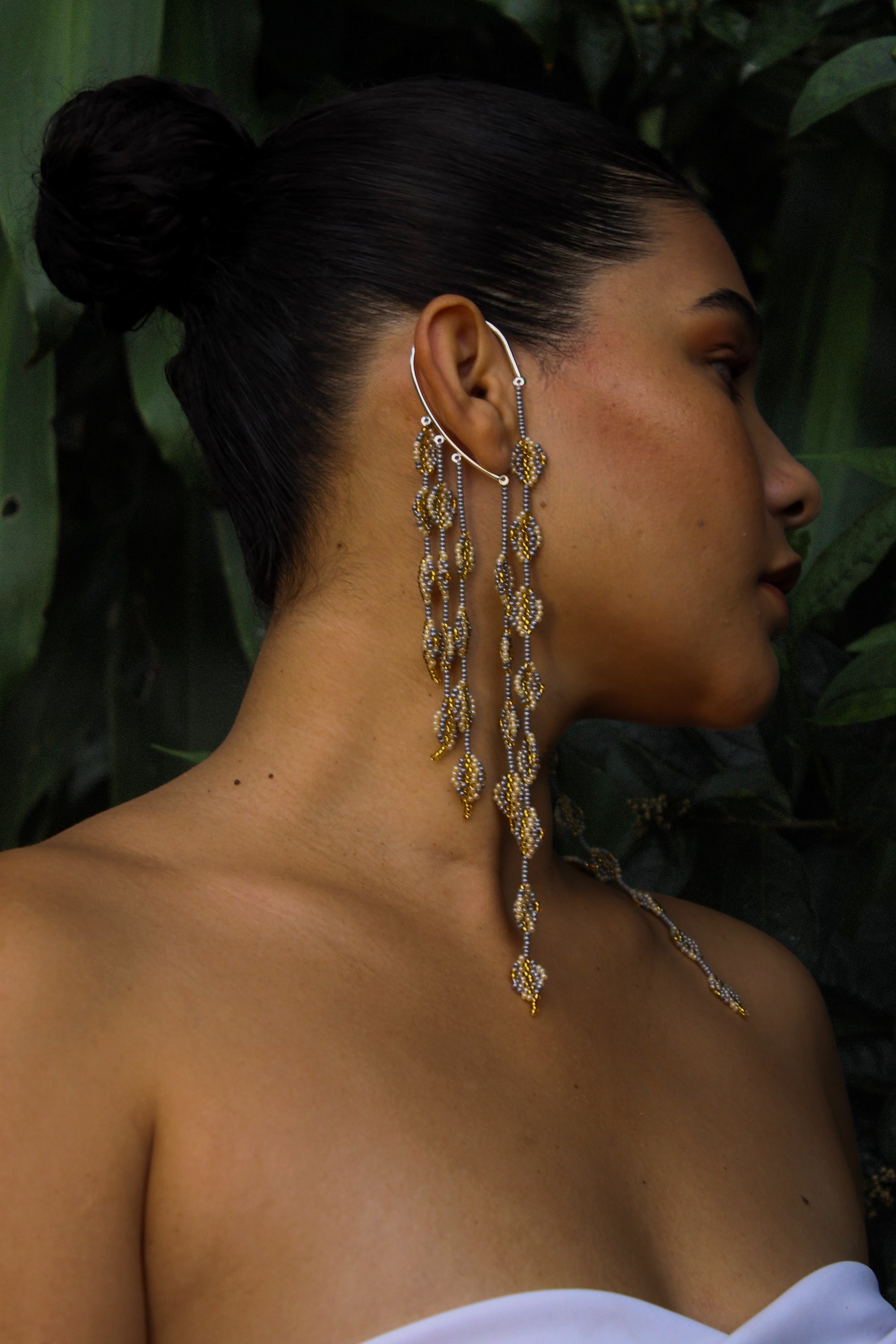 Woman wearing long, dangling earrings with a natural background